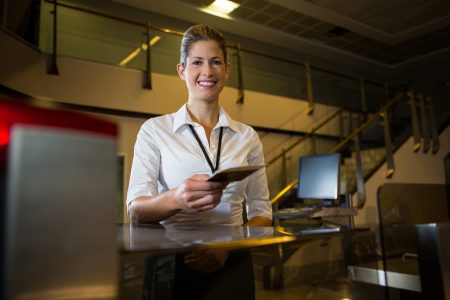 Portrait of female staff holding boarding pass and passport at airport terminal